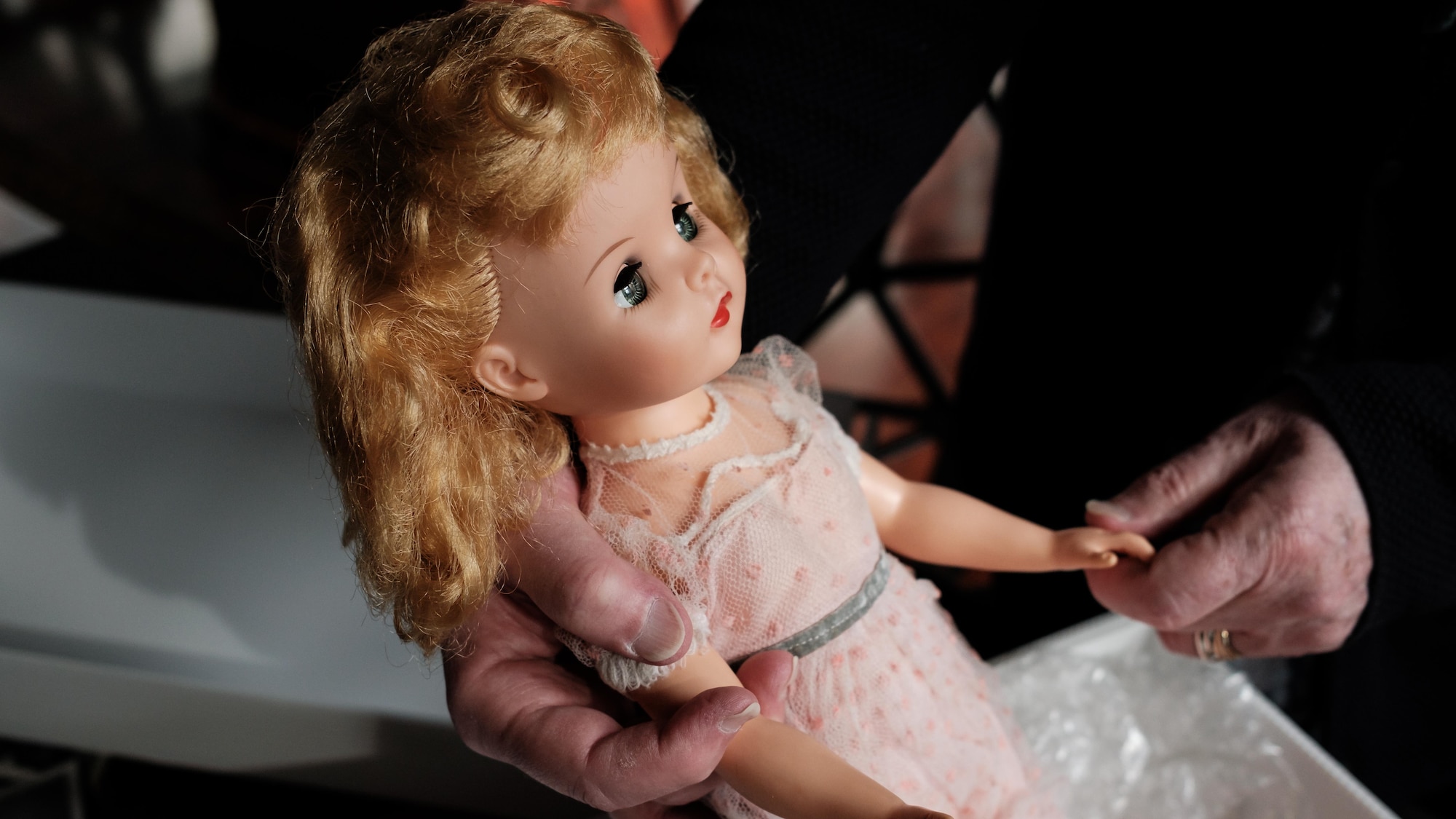 Jean-Claude Poitras tient délicatement sa poupée aux cheveux blonds.