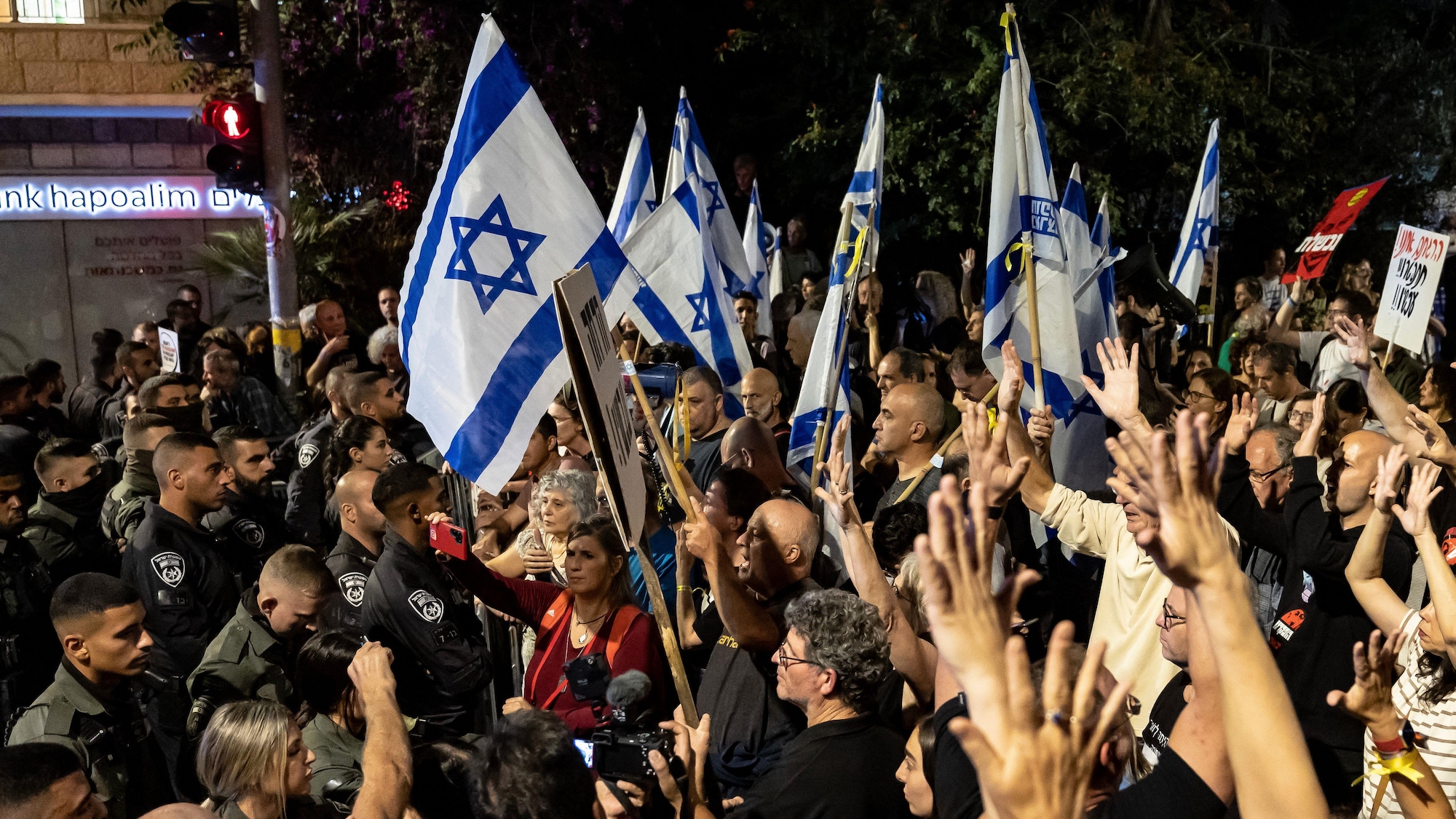 Des personnes manifestent avec des drapeaux israéliens.