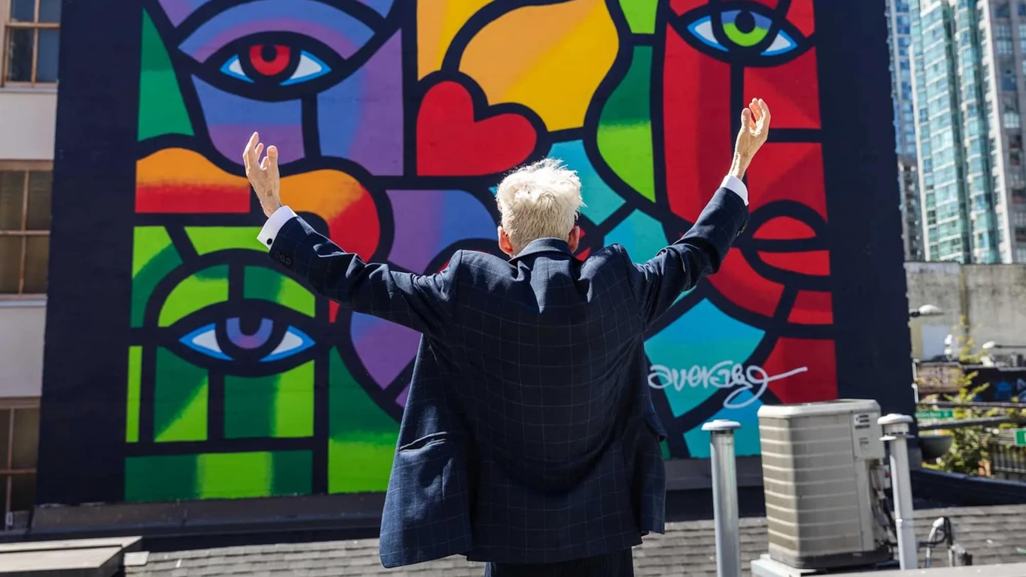 joe Average, les bras grands ouverts devant sa murale "40 years later", à Vancouver.