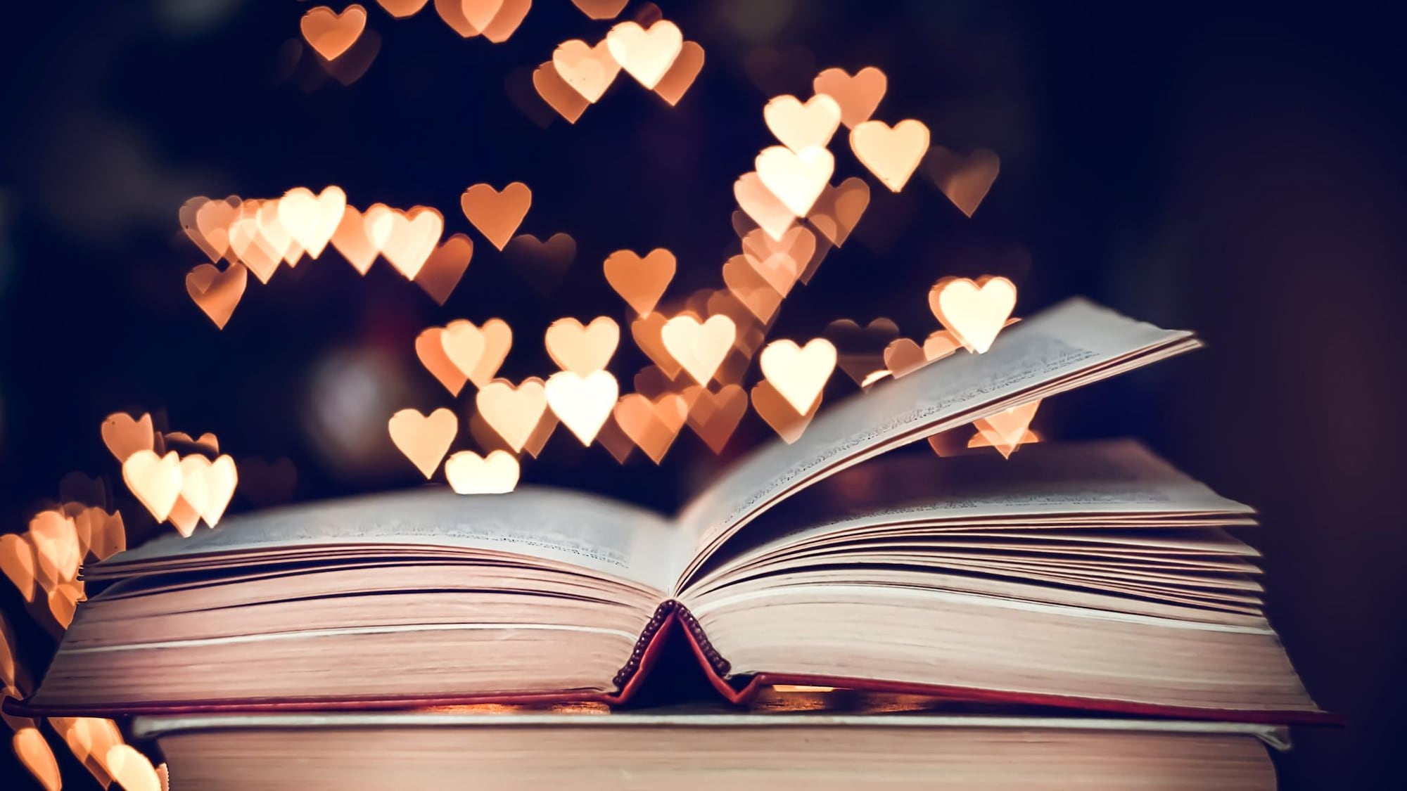 Des coeurs illuminés planent au-dessus de livres.