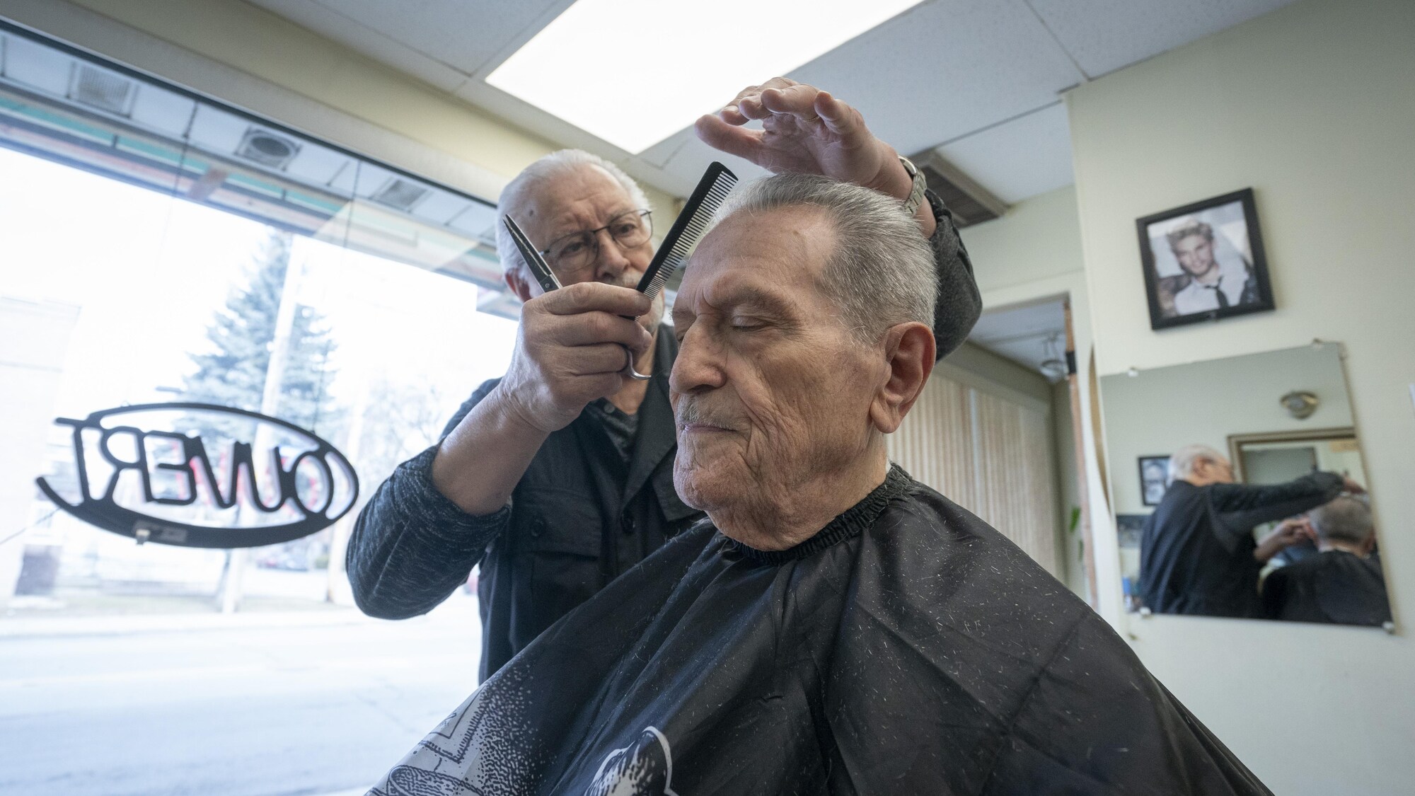 Luigi Broccoli coupe les cheveux d'un homme âgé.