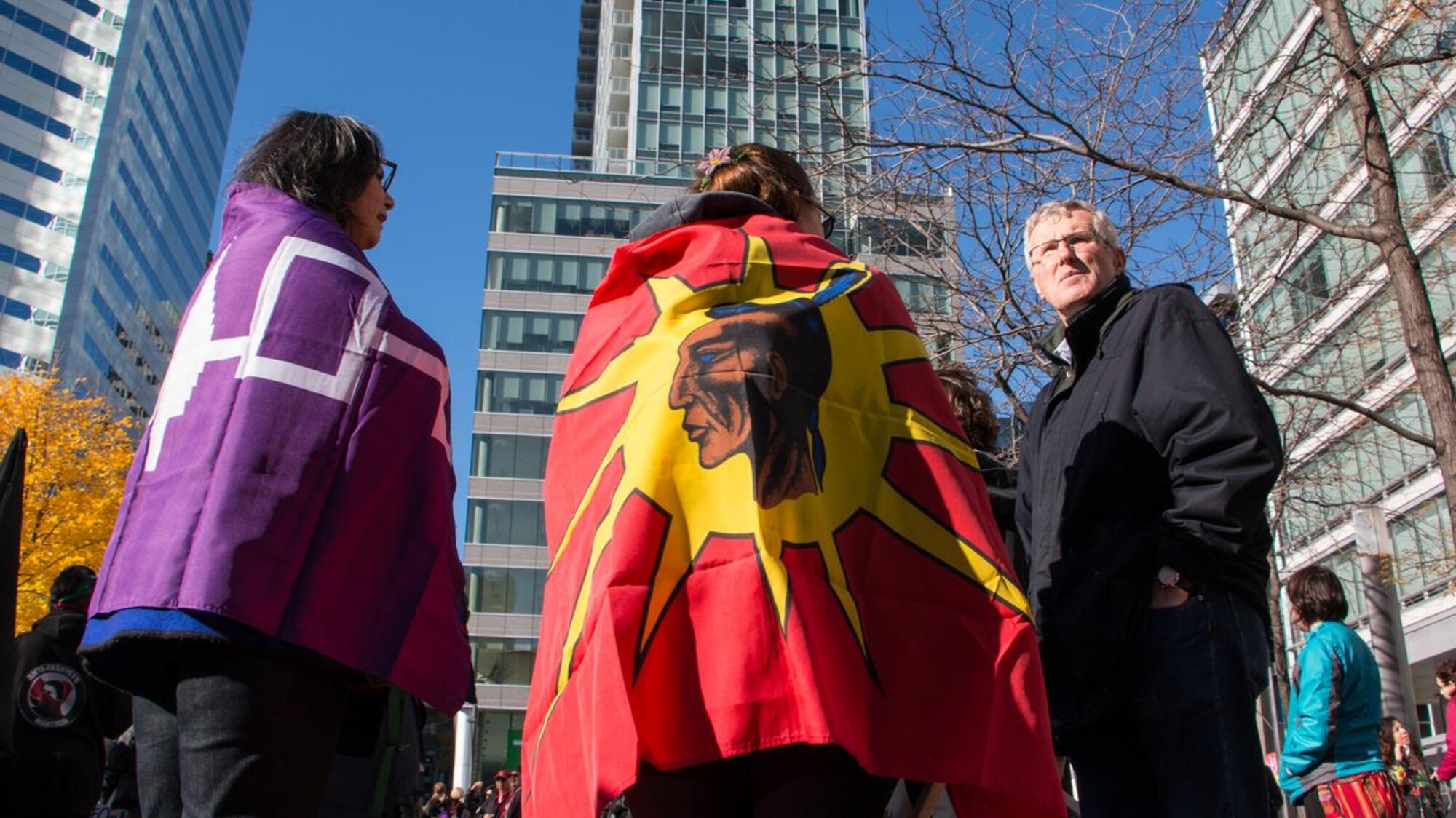 Des femmes, de dos, portant des drapeaux sur les épaules, lors d'une manifestation à Montréal en 2016.
