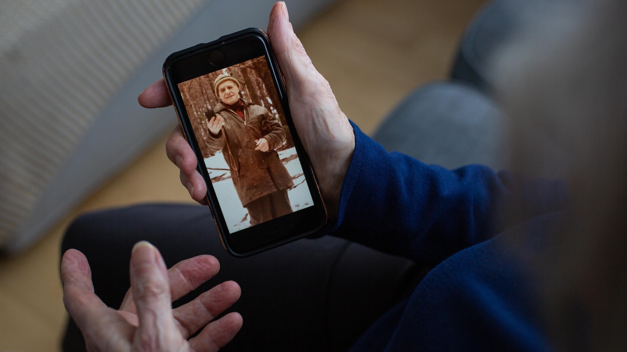 Une photo du père de Micheline Lanctôt apparaît sur un téléphone cellulaire, qu'elle tient dans une main.