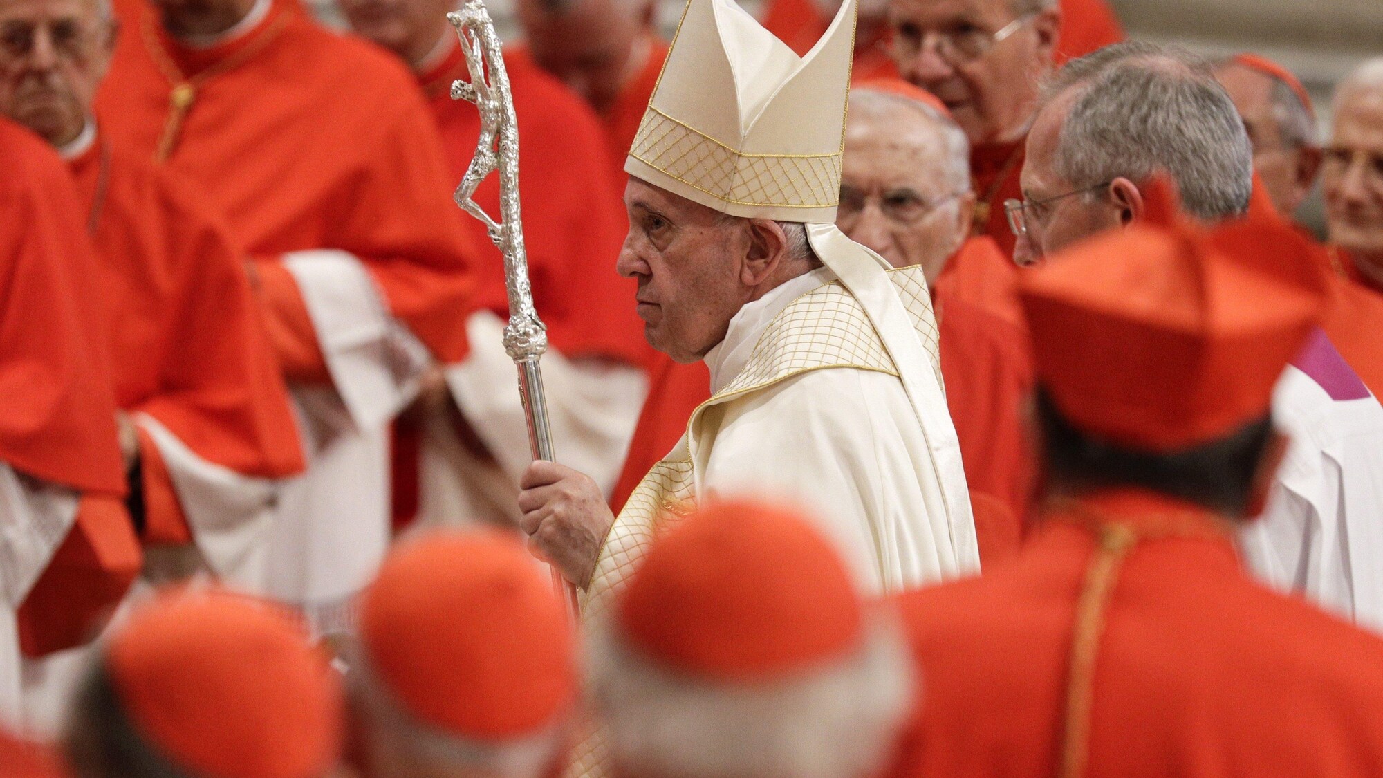Le pape François porte sa crosse et sa mitre, en procession dans la basilique Saint-Pierre, entourés de cardinaux en tenue liturgique rouge et blanche.