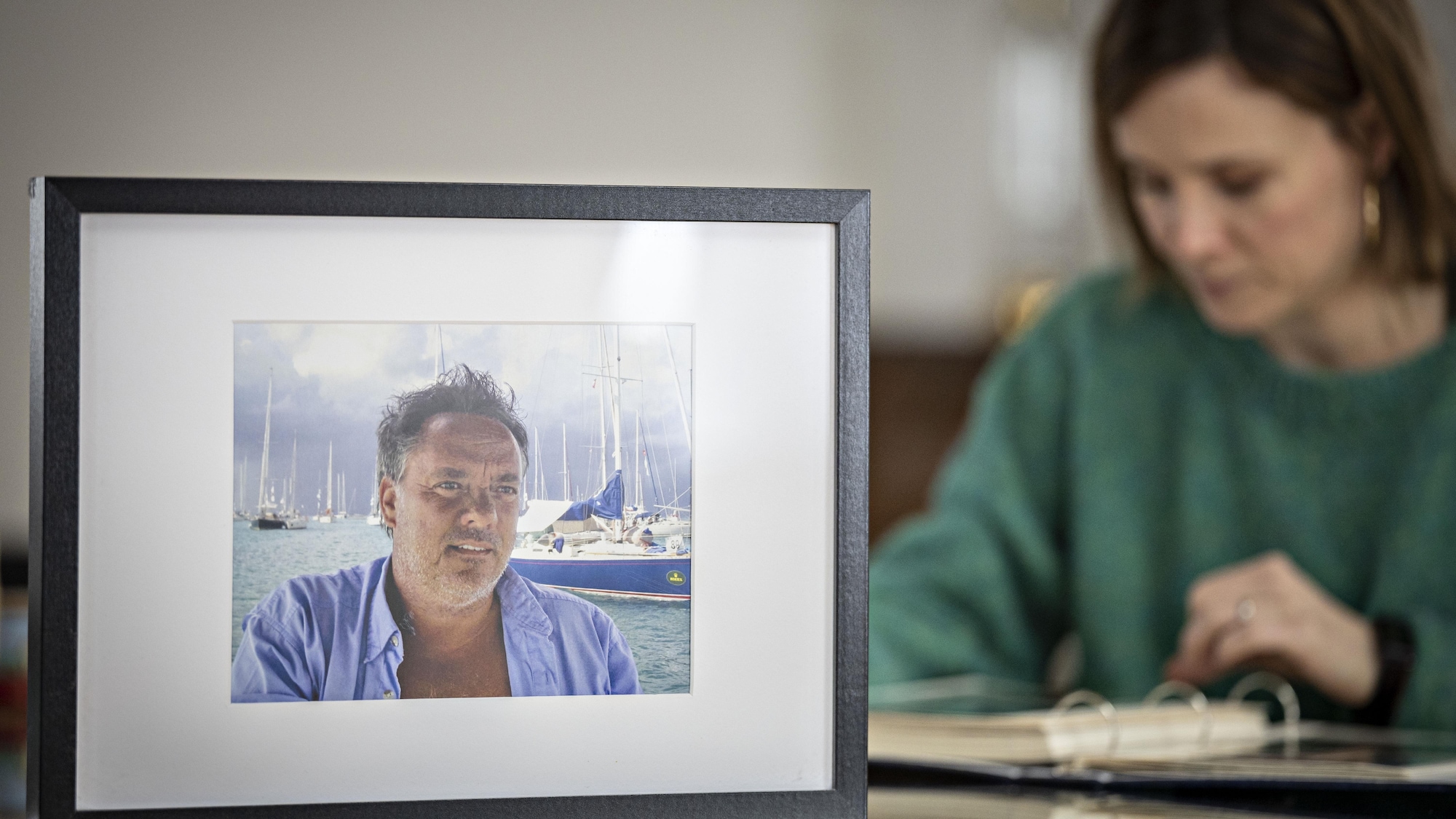 Une femme regarde un album de photos derrière un cadre montrant la photo d'un homme.