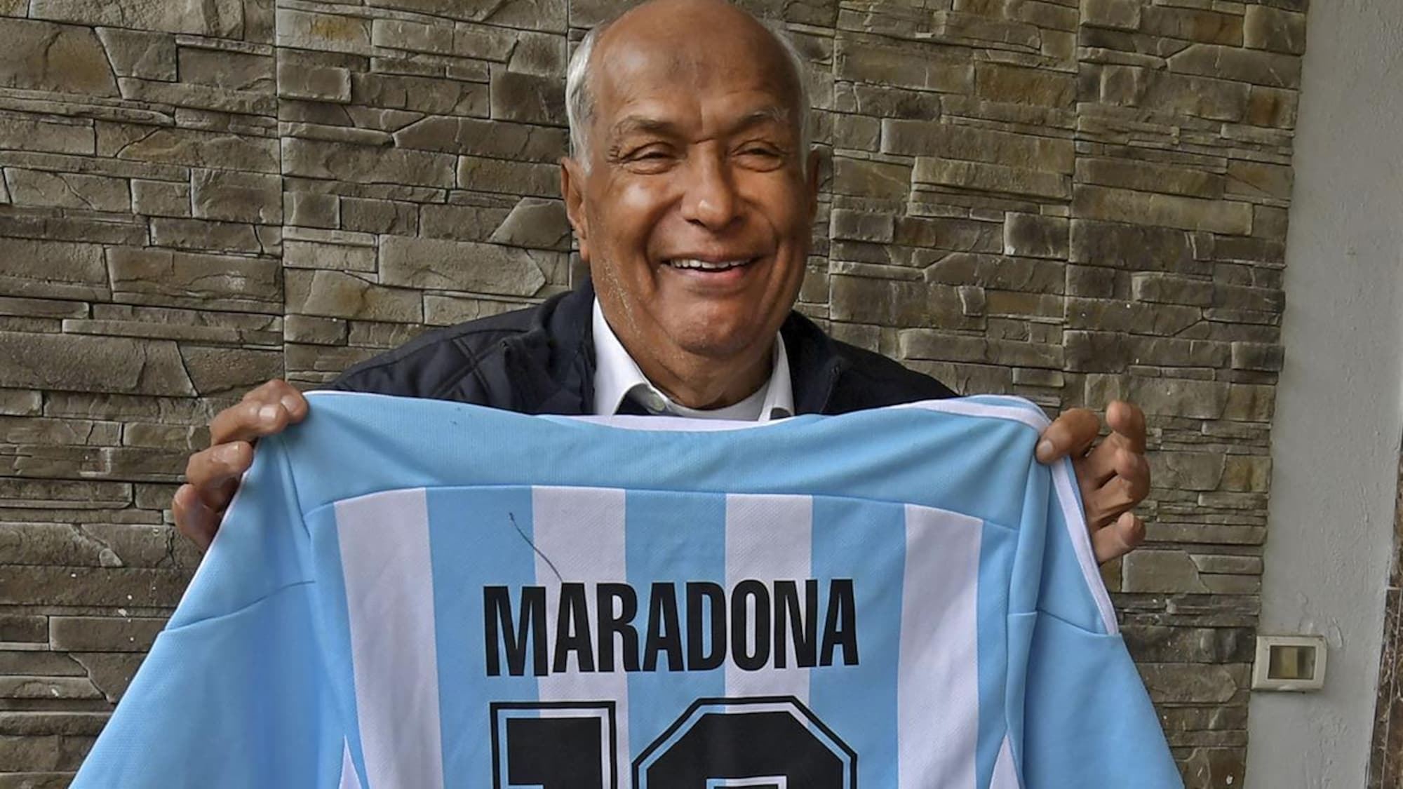 Il sourit en montrant le dos d'un chandail bleu et blanc avec le no 10 de Maradona