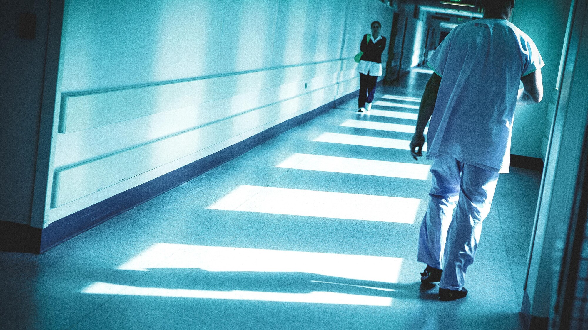 Deux personnes se croisent en marchant dans un couloir d'hôpital.