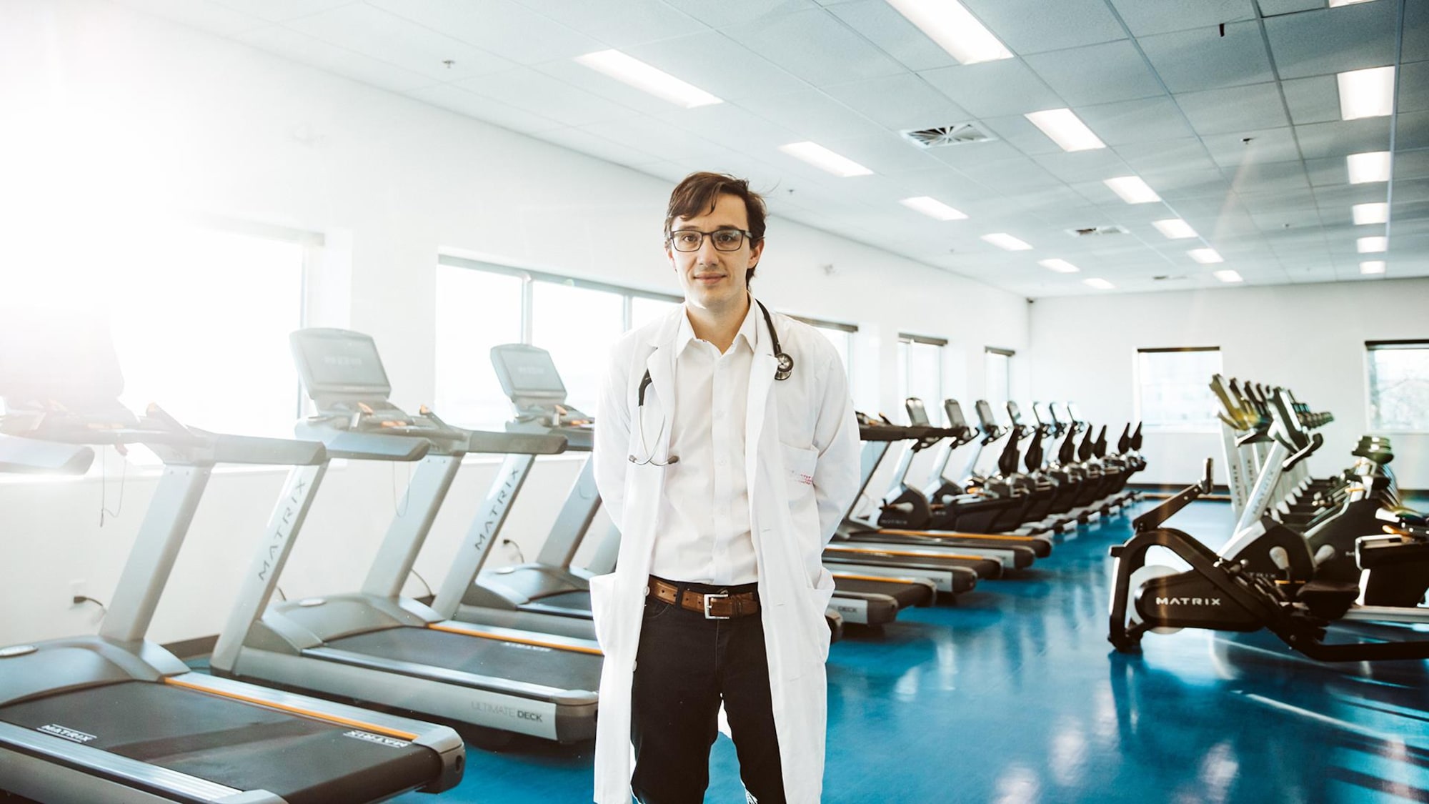 Le médecin se tient debout devant une série de tapis roulants.