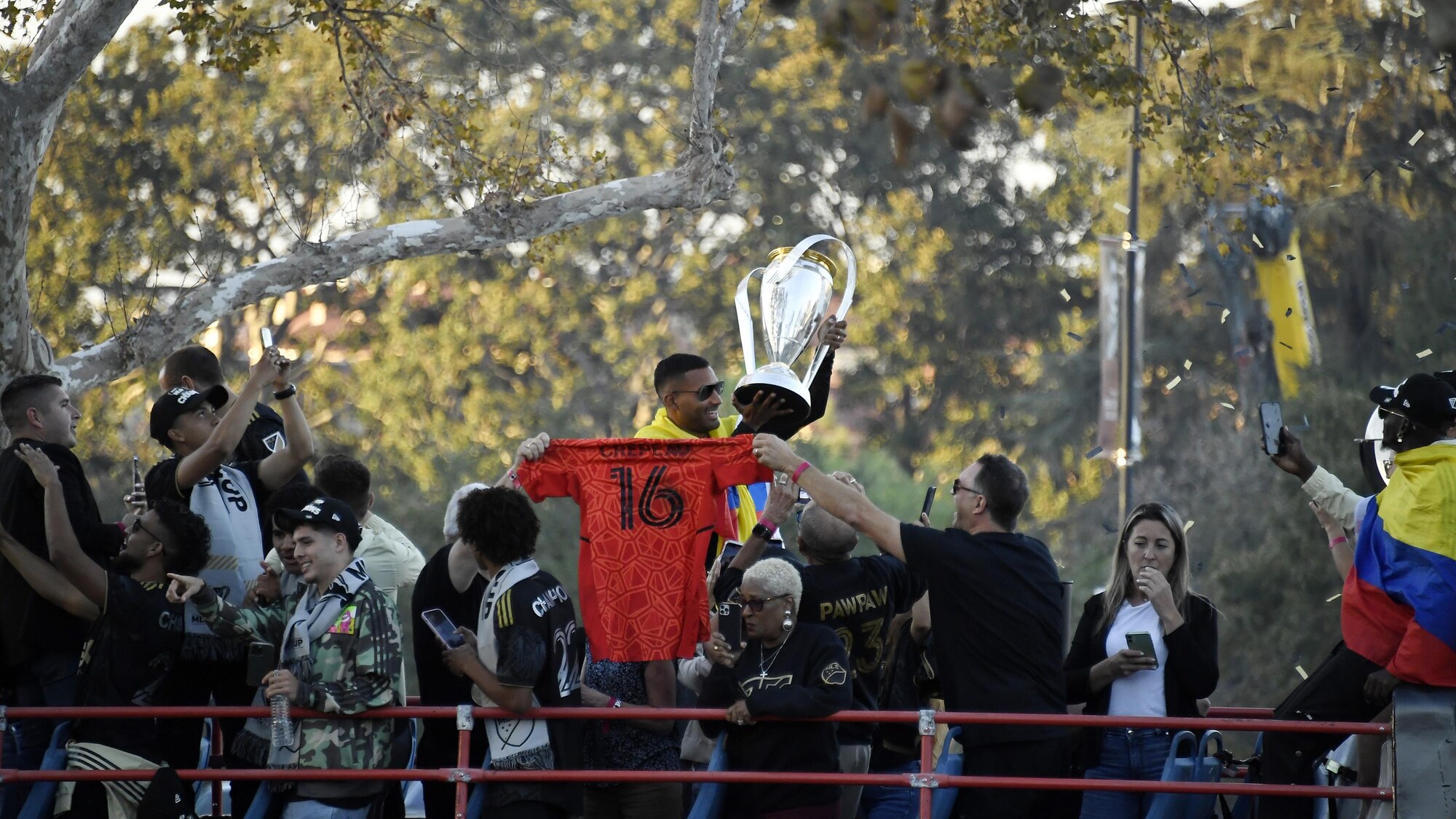 Une équipe championne sur le le toit d'un autobus. Un joueur tient le trophée, près duquel on voit un chandail rouge avec le no 16 de Maxime Crépeau