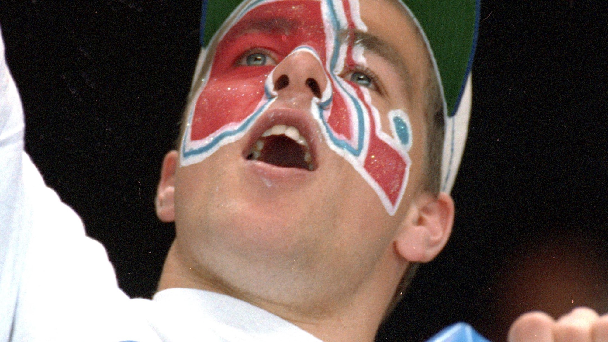 Un partisan affichant le logo des Nordiques peint sur son visage crie.