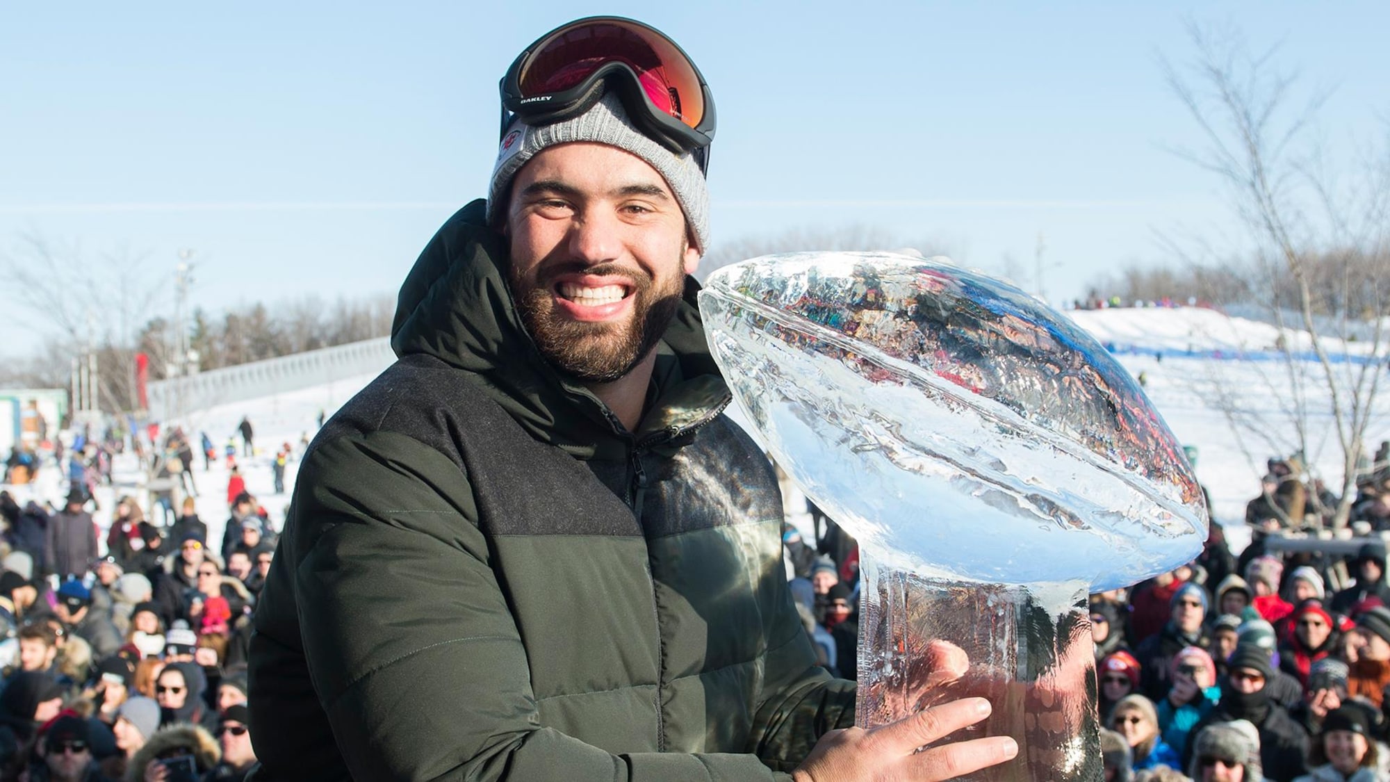 Un homme sourit en tenant une réplique en glace d'un trophée.