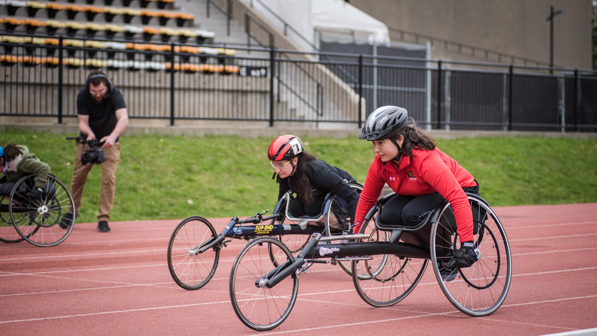 Une femme en rouge dispute une course de fauteuil roulant à côté d'une jeune athlète dans le couloir voisin