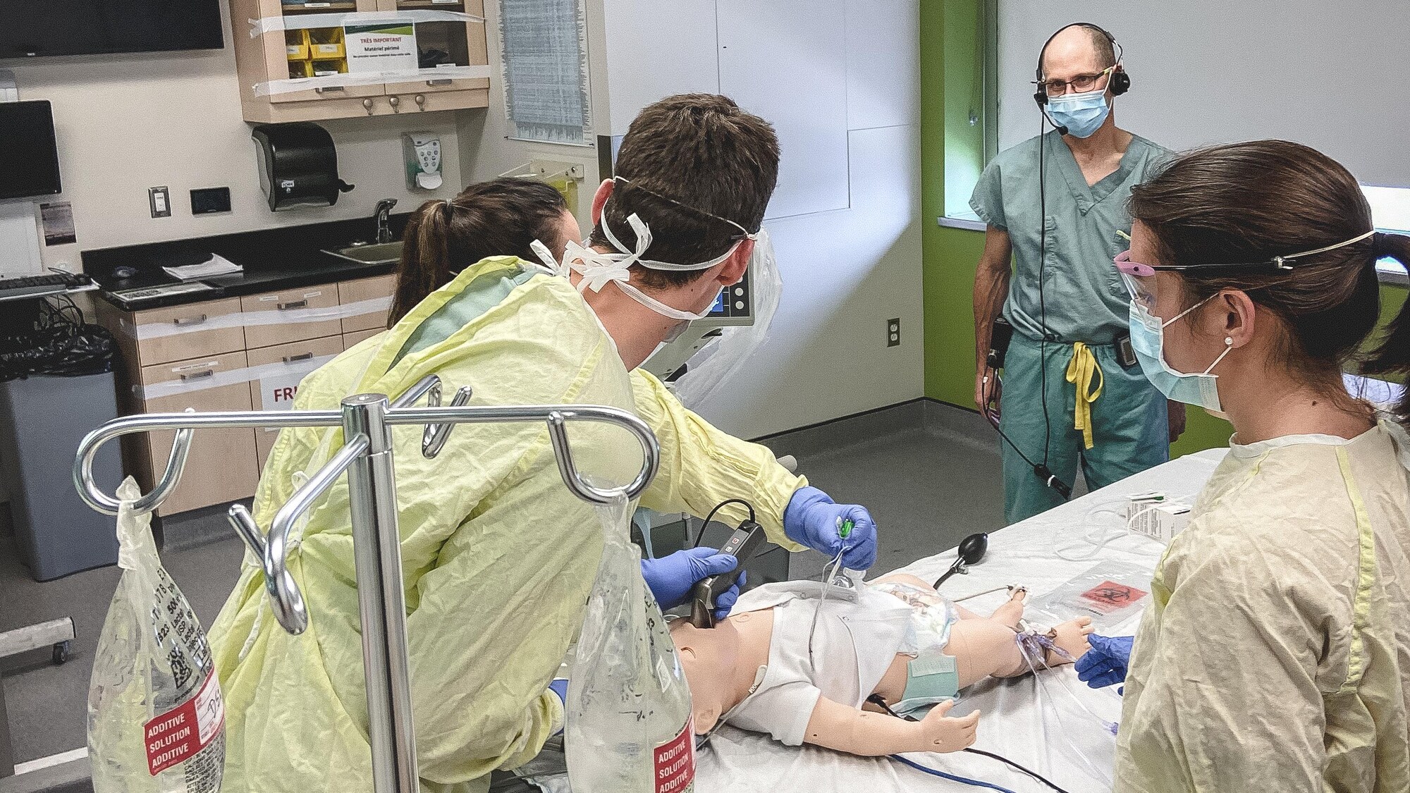Le Dr Sébastien Roulier (au fond) supervise une simulation d'intervention auprès d'un jeune enfant, personnifié par un mannequin.