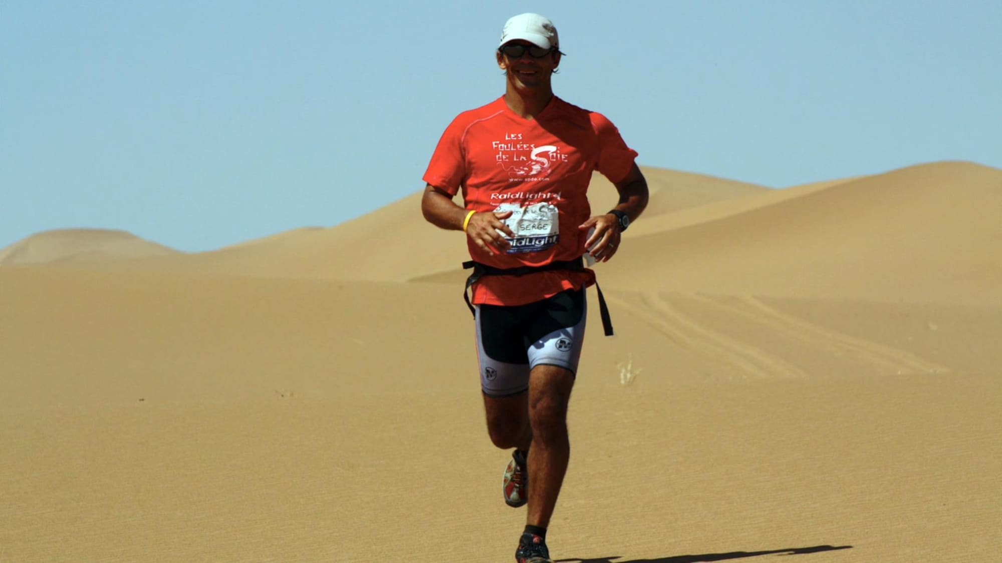 Un homme court dans un désert de sable.