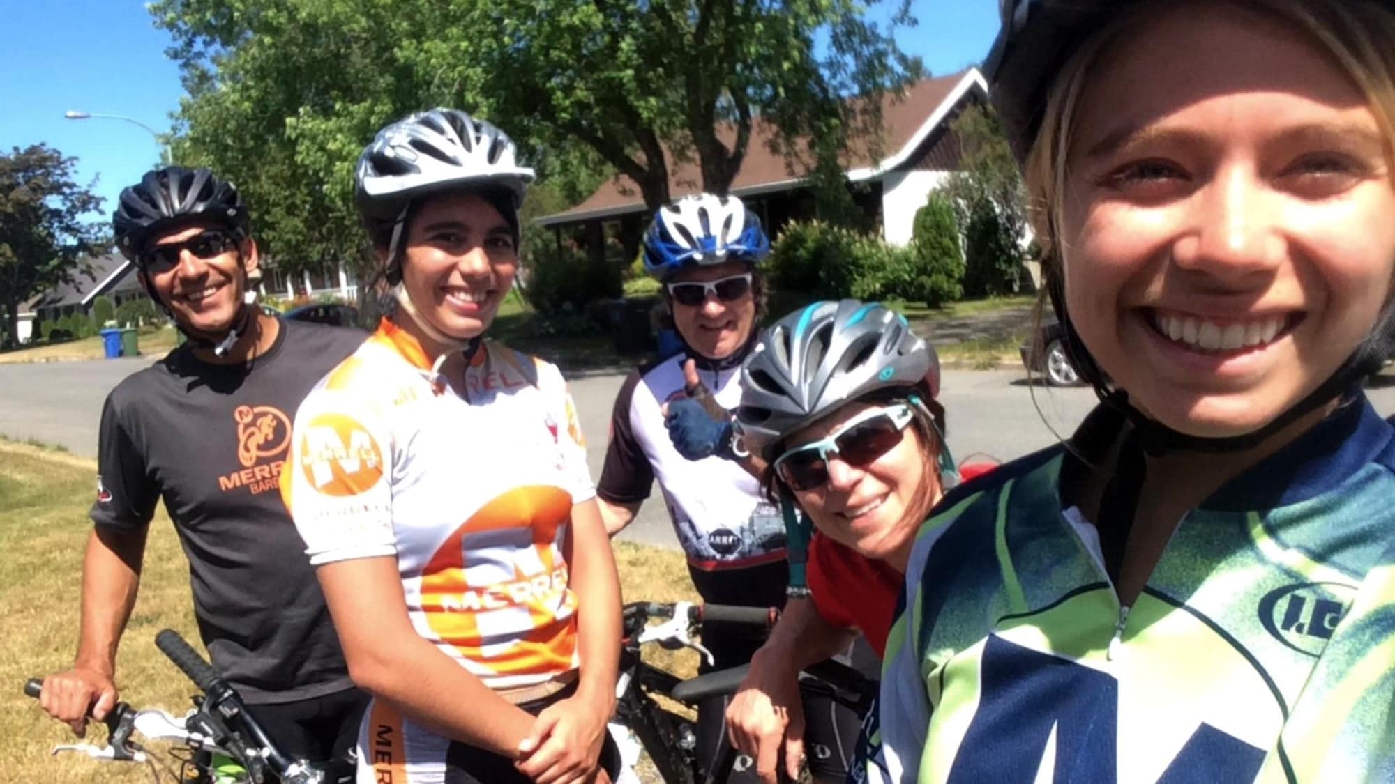 Cinq personnes en vêtements en vélo regardent la caméra en souriant.