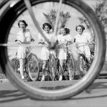 Vue de quatre jeunes filles à vélo à travers les rayons de roue d'un autre vélo.