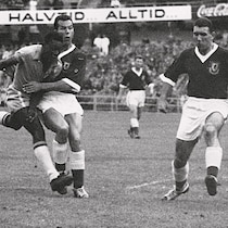 À gauche, Pelé lance le ballon près de deux joueurs de soccer adverses.
