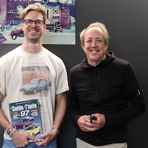 Julien Poirier-Malo a le Guide de l'auto 97 dans les mains, accompagné de l'auteur de ce guide, le chroniqueur automobile Gabriel Gélinas. Les deux personnes sont souriantes. 