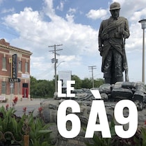 Une statue représentant des combattants de la Première Guerre mondiale se trouve sur le terre-plein devant un bâtiment en brique rouge avec une enseigne où il est écrit « Belgian Club ».