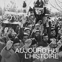 Des partisans de l'ayatollah Khomeini manifestent dans une rue; certains d’entre eux brandissent des affiches de l'ayatollah.