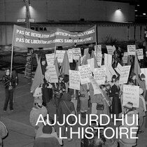 Des personnes manifestent dans une rue en tenant des pancartes.