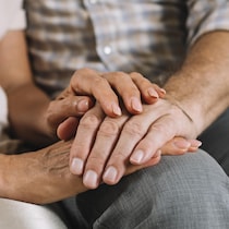 Des mains sont une par-dessus l'autre sur le genou d'une personne.