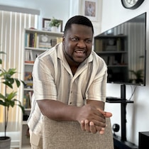 Thélyson Orélien, souriant, appuyé sur le dossier d'une chaise.