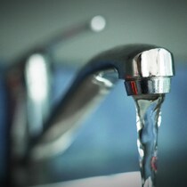 Un robinet laisse couler un filet d'eau.