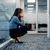 Une femme est accroupie dans le couloir d'un espace de travail.