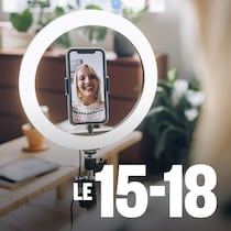 Une influenceuse souriante installe son téléphone portable et filme un vlog dans un salon.