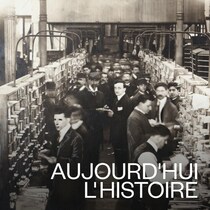 Dans un bureau de poste, des employés classent le courrier dans des rangées de casiers.