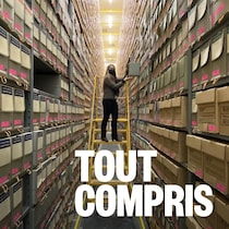 Une personne sur une échelle au milieu de centaines de boites d'archives rangées sur des étagères.