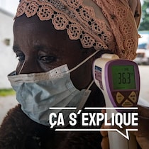 Quelqu'un prend la température sur la tempe d'une femme qui porte un masque d'intervention.