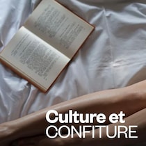 un livre ouvert et des jambes sur un drap de lit.