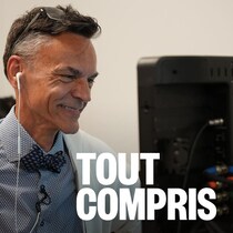 Un homme souriant qui regarde un écran.