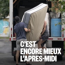 Deux hommes transportent un matelas dans la boîte d'un camion de déménagement.