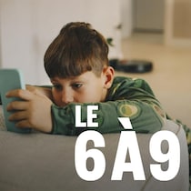Un jeune garçon regarde son cellulaire en pyjama.