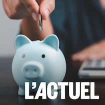 Photo d'une personne qui s'apprête à mettre une pièce dans une tirelire en forme de cochon. La personne est assise à un bureau avec une calculette devant elle.