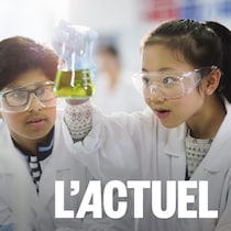 Les enfants regardent une jeune fille asiatique tenir une fiole avec une réaction chimique.