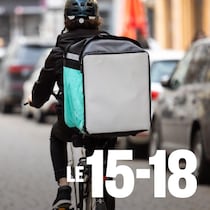 Une personne en vélo transporte un sac isotherme sur son porte-bagages.