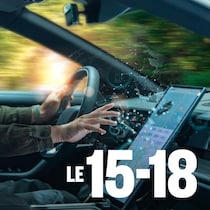 Une personne conduit une voiture d'une main et de l'autre appuie sur un écran.