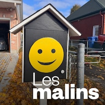 Une boite de livres sur le bord d'une rue. Elle affiche un grand bonhomme sourire jaune.