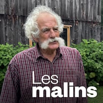 Un homme qui pose devant un vieil édifice en bois.
