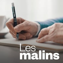 Gros plan des mains d'une personne âgée qui écrit dans un livre.
