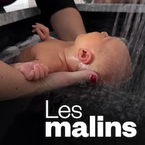 Les mains d'une femme qui supportent un bébé plongé dans l'eau.