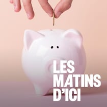 Gros plan d'une main qui dépose une pièce de monnais dans une banque en forme de cochon.