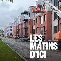 Une enseigne de logements à louer dans une rue avec des bâtiments en construction.