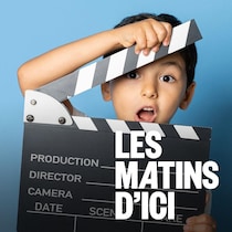 Un jeune garçon qui tient une claquette de cinéma devant lui.