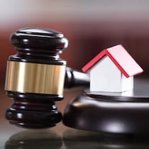 Un maillet de juge et une maison miniature dans une cour de justice.