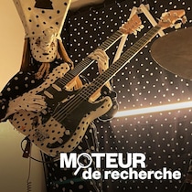 Un des membres du groupe Angine de Poitrine joue sur une guitare à deux manches.